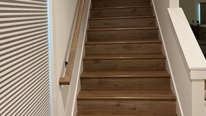Eine Holztreppe mit weißen Geländern und einem Bild an der Wand darüber.