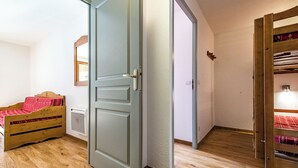 A room with a wooden bed, a closed door, and a wooden shelf unit with a light. - Apartment for 4 to 6 people in Albiez-Montrond (Albiez-Montrond)