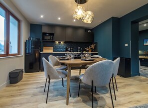Una cocina moderna con paredes azul oscuro, una mesa de comedor de madera y sillas tapizadas en gris.