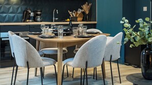 Una cocina moderna con armarios oscuros, una mesa de comedor para cuatro personas y una lámpara colgante original.