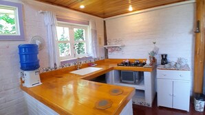 Une cuisine compacte dotée d’un plan de travail en bois, d’un évier, d’une cuisinière et d’un petit réfrigérateur.