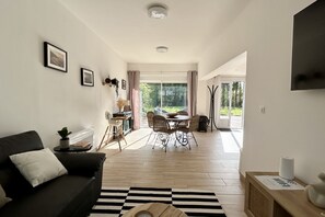 Een moderne woonkamer met een bank, een eethoek met stoelen, een salontafel en een groot raam.