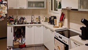A compact kitchen with white cabinets, a built-in oven, a stovetop, and a small window.