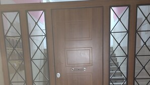 A wooden door with a metal security gate, a handle, and a keyhole.