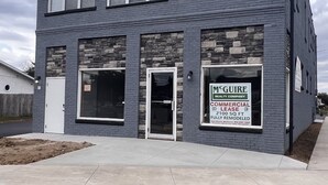 Un bâtiment à deux étages, orné d’une enseigne commerciale pour la société McGuire Realty Company, avec une façade en pierre et de nombreuses fenêtres.