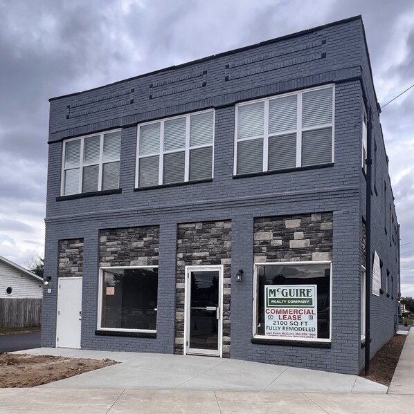 Un bâtiment à deux étages, orné d’une enseigne commerciale pour la société McGuire Realty Company, avec une façade en pierre et de nombreuses fenêtres.
