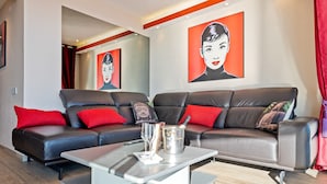 Un salon moderne avec un canapé d’angle, une table basse et des œuvres d’art accrochées aux murs.