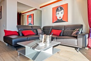 A modern living room with a sectional sofa, a coffee table, and artwork on the walls.