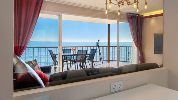 Un balcon avec vue sur la mer, une table avec des chaises et un canapé.
