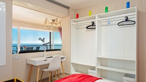 Une chambre avec un bureau, un lit, une armoire, une fenêtre donnant sur un beau paysage et un lustre.