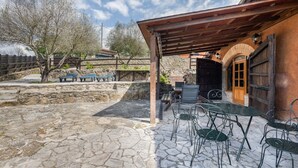 Eine Außenpatio mit Steinboden, Metallstühlen und einer Holzpergola.