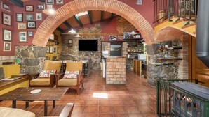 Ein rustikales Interieur mit Kamin aus Stein, Holzmöbeln und einem Backsteinbogen.