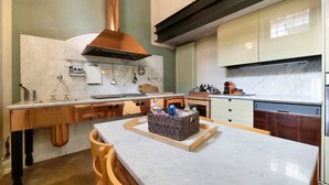 A kitchen with a marble countertop, copper range hood, and wooden cabinets. - Holiday Apartment "Viasambuco" with Private Terrace & Wi-Fi (Iseo)