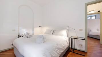 Ein Schlafzimmer mit einem großen Bett, einem Nachttisch mit Lampe und einem Spiegel.