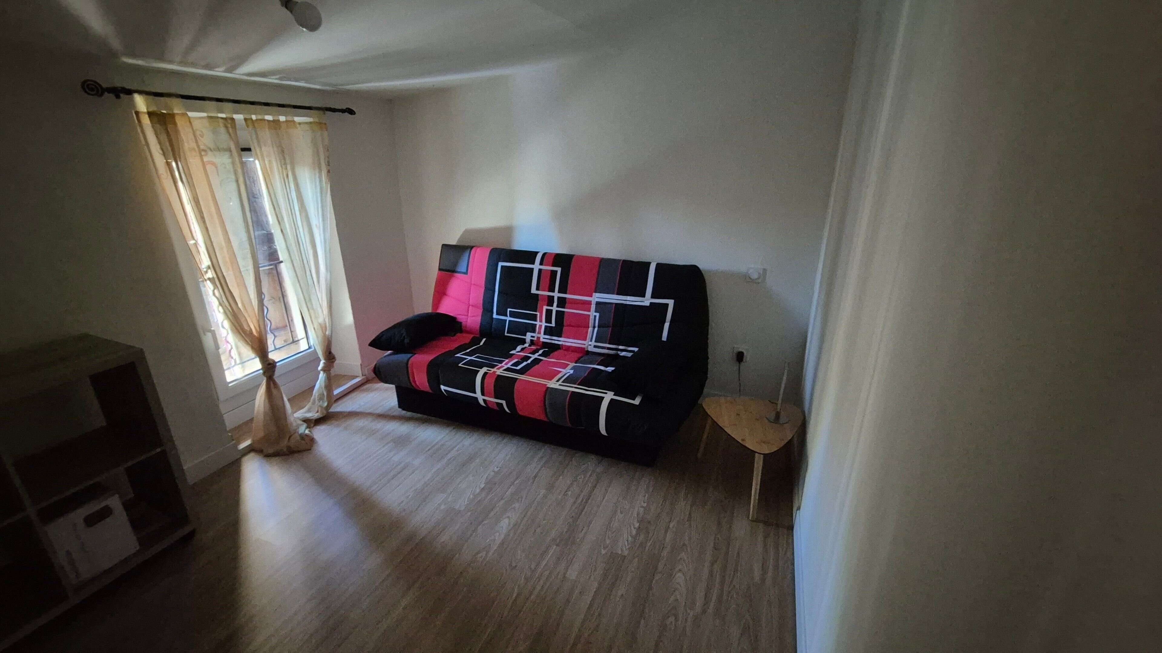A living room with a sofa, a small table, and a window with curtains.
