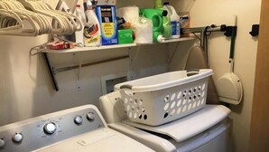 A laundry area with a washing machine, a dryer, and a shelf with cleaning supplies.