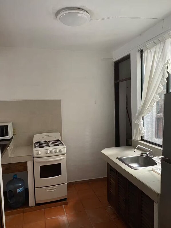 A compact kitchen with a gas stove, oven, and a microwave. - Garden view near pool
(Puerto Vallarta)