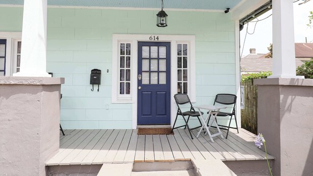 A porch with a blue door marked "614", two chairs, and a small table.