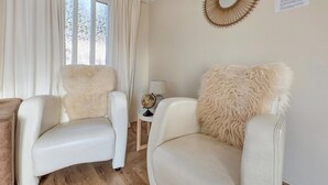 Deux fauteuils en cuir blanc dotés de coussins moelleux, un globe terrestre posé sur une petite table et un élément décoratif mural.