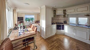 Une cuisine spacieuse dotée d’un plancher en bois, de meubles blancs et d’un coin repas avec une table en bois et des chaises en cuir.