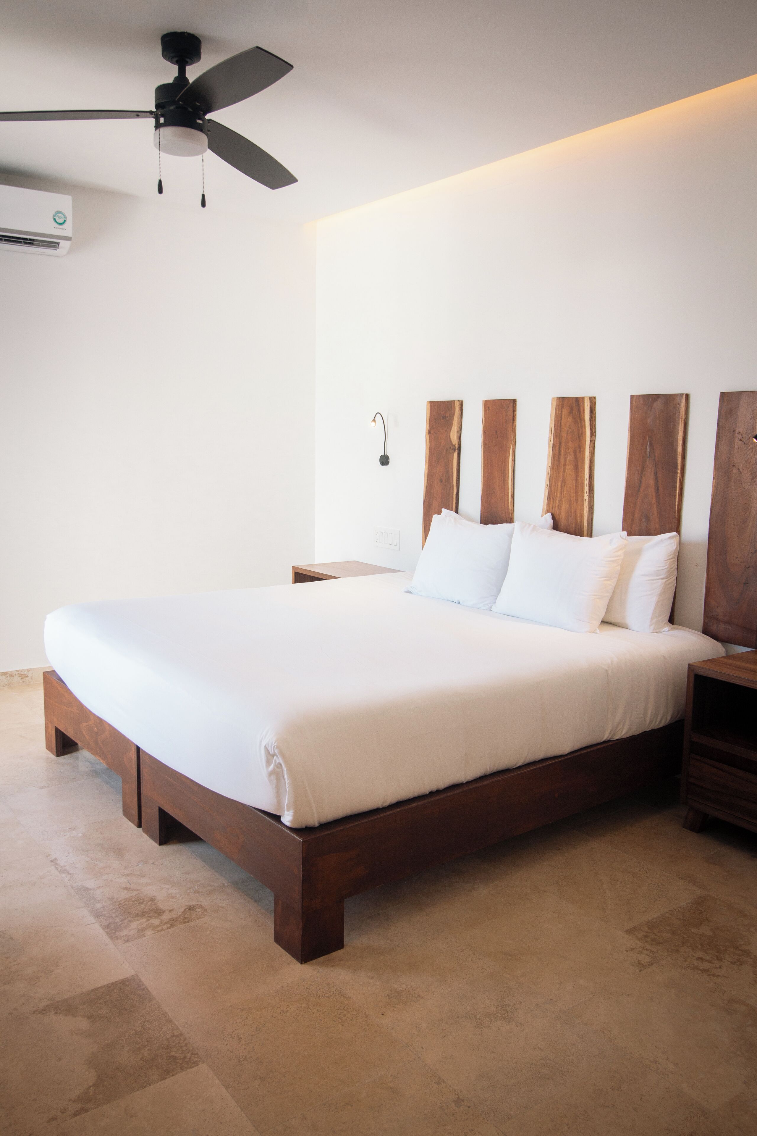 Una camera da letto con un letto grande, una testiera in legno, comodini e una ventola a soffitto.