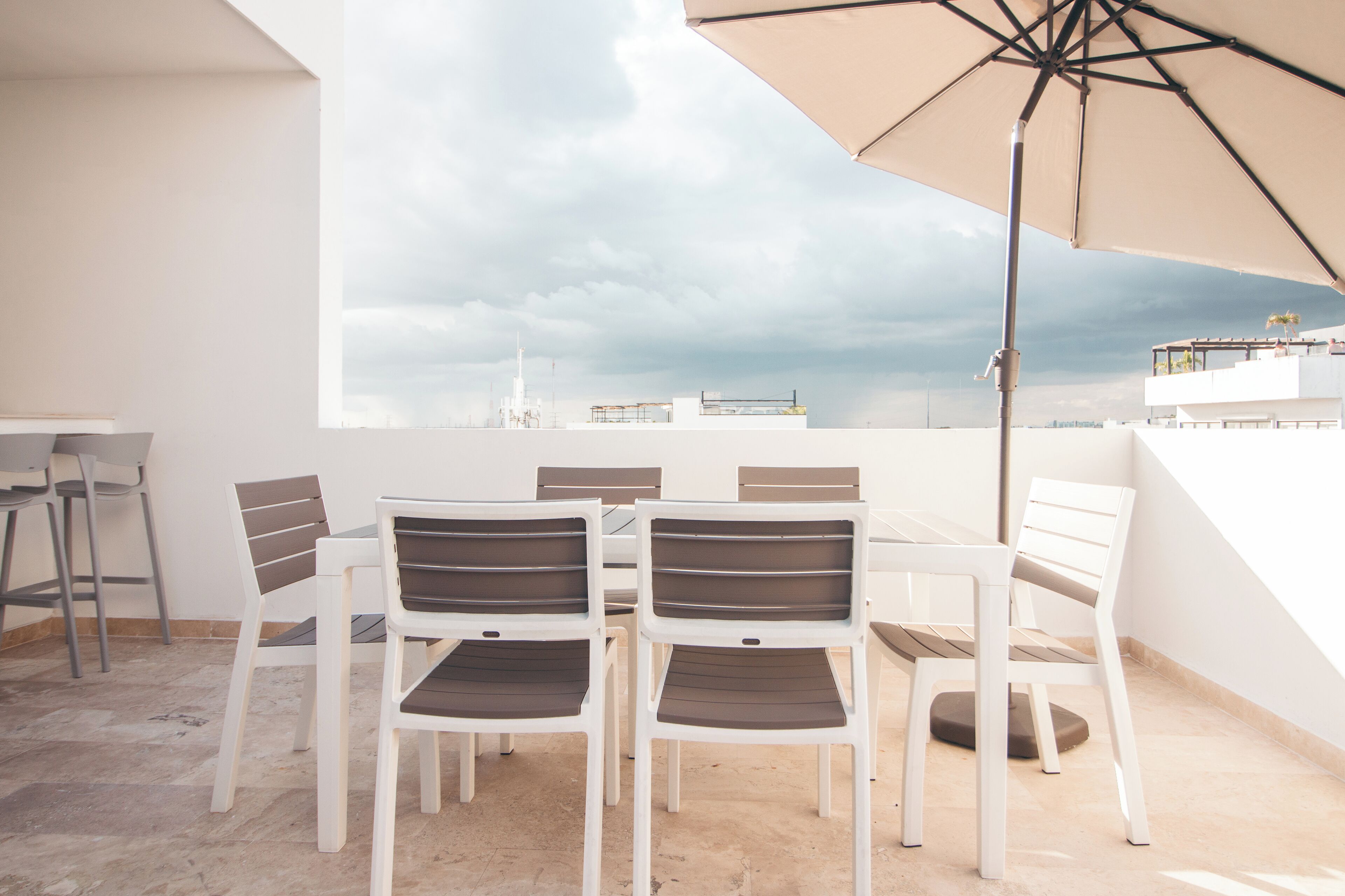 A dining area with a table and chairs, a large umbrella, and a view of the city skyline.