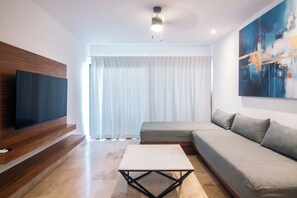 Ein modernes Wohnzimmer mit einem Ecksofa, einem flachbildfernseher, der an einer Holzvertäfelung angebracht ist, einem Couchtisch und einem großen abstrakten Gemälde an der Wand.