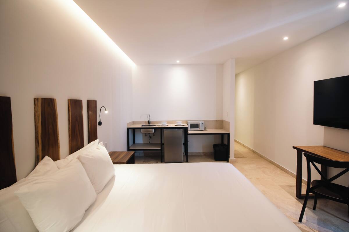 Ein Hotelzimmer mit einem Bett, einem Schreibtisch mit Mikrowelle, einem Fernseher und einer kleinen Mülltonne.