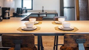 A modern kitchen with a dining table, chairs, and hanging pendant lights.