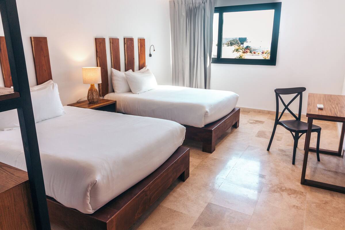 Ein Hotelzimmer mit zwei Betten, einem Schreibtisch und einem Stuhl.