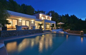 Relax by the outdoor pool surrounded by comfortable lounge chairs and a well-lit patio.