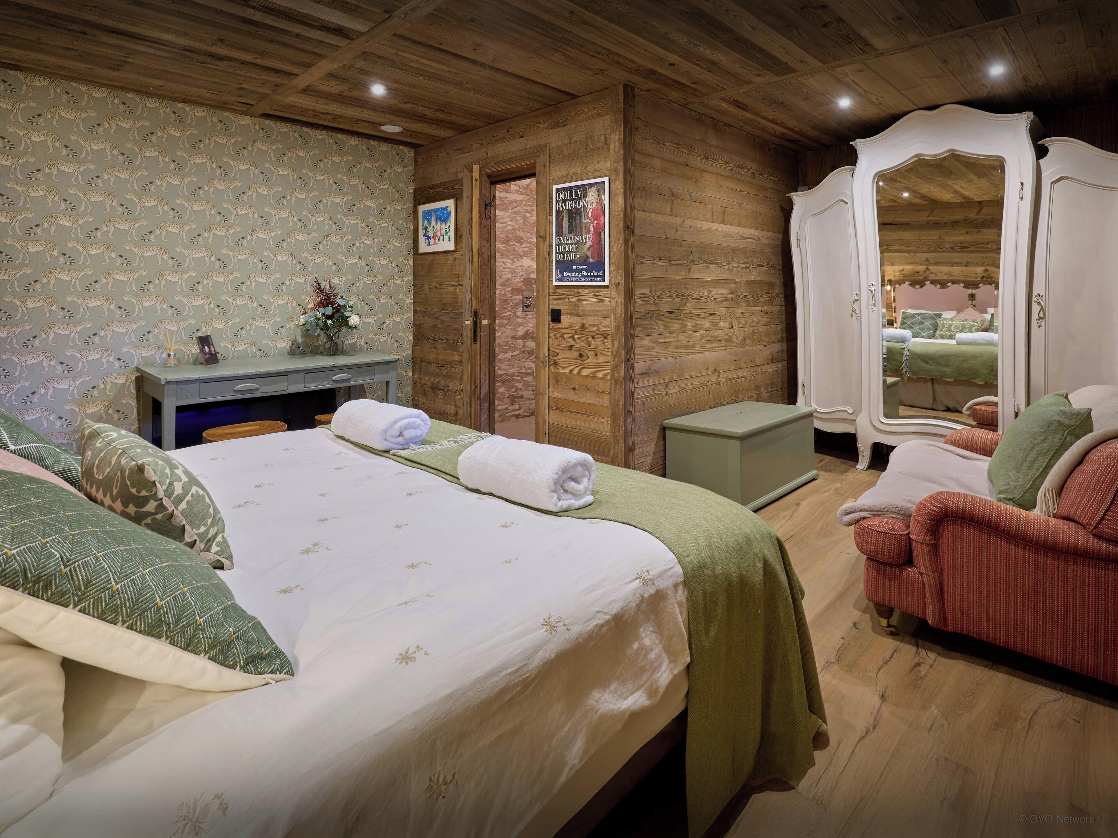 Een knus slaapkamer met een bed, bureau en spiegel.