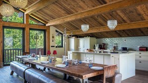 A wooden dining area with a long table, benches, and hanging chandeliers. - Chalet Wonderland - Amazing chalet for 13 with summer pool - OVO Network (Séez)
