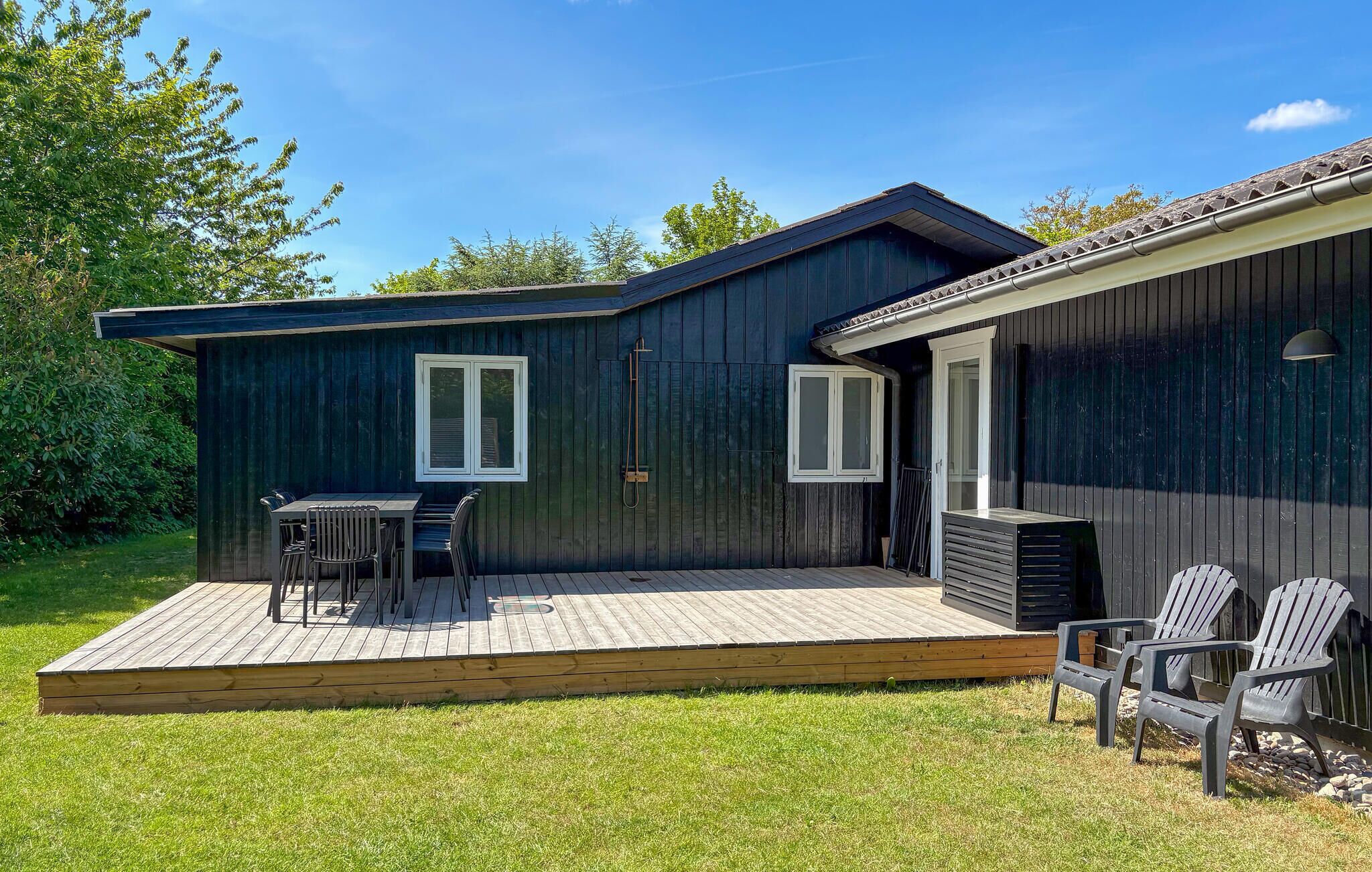 Une maison en bois avec une terrasse, deux fenêtres et une porte.