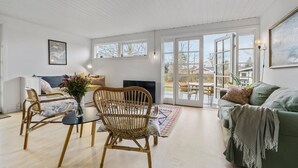 A spacious living room with a large window, a fireplace, and a green sofa. - 3 bedroom nice home in Dronningmølle (Dronningmølle)