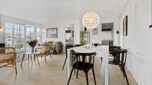 A spacious living area with a dining table, chairs, and a large chandelier. - 3 bedroom nice home in Dronningmølle (Dronningmølle)