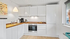 A modern kitchen with white cabinets, a wooden countertop, a built-in oven, and a window with a view of the outside. - 3 bedroom nice home in Dronningmølle (Dronningmølle)