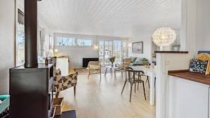 A spacious living area with a large window, a fireplace, and a dining area with chairs and a table. - 3 bedroom nice home in Dronningmølle (Dronningmølle)