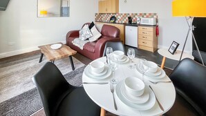 Ein modernes Wohnzimmer mit Essbereich, einer Couch, einer Kaffeemaschine und einer Mikrowelle.