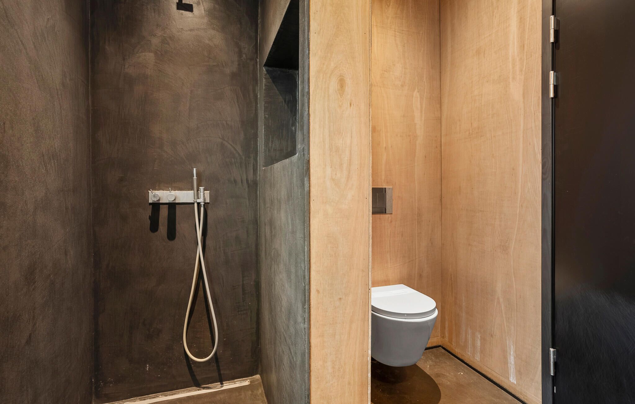 Ein modernes Badezimmer mit Dusche, Toilette und einer Holzwand.