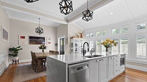 A modern kitchen with a central island, white cabinetry, and a built-in dishwasher.