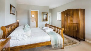 Un dormitorio con cama de madera, un armario y un baño visible a través de una puerta abierta.