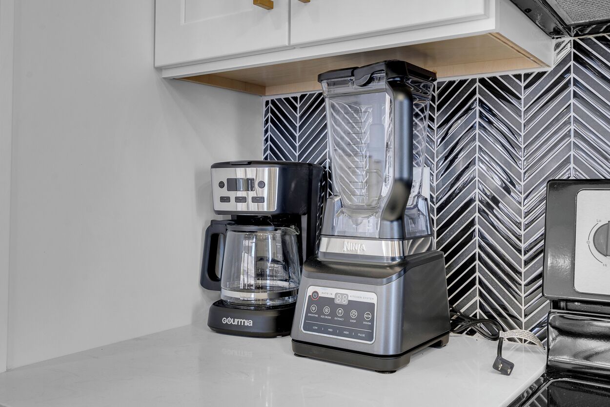 A kitchen with a coffee maker, a blender, and a microwave.