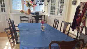 A dining room with a blue tablecloth, wooden chairs, a chandelier, and a vase with flowers.
