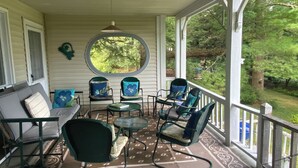 A covered porch with a sofa, chairs, and a table.