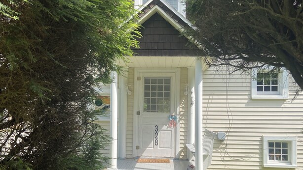 A house with a front porch, a mailbox, and a number '328' on the door.