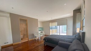 Een moderne slaapkamer met een groot bed, een klein bureau en uitzicht buiten.