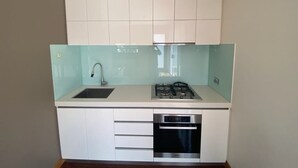 Een kleine keuken met een spoelbak, kookplaat en vaatwasser.