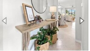 Un pasillo moderno con una consola de madera, un espejo redondo y dos cestas tejidas con plantas.