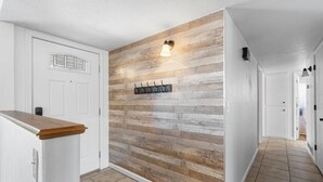 A hallway with a wooden wall, a coat rack, and a light fixture.